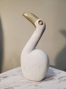 White Pelican Bird sitting looking up curiously. The bird has a beautiful gold beak. Colors Include: Gold, White. 