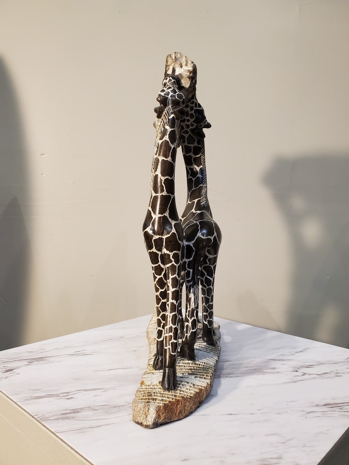 Two giraffes eating from a tree. The giraffes have a beautiful pattern of brown circles outlined in white. Colors include: Brown, White, Tan.